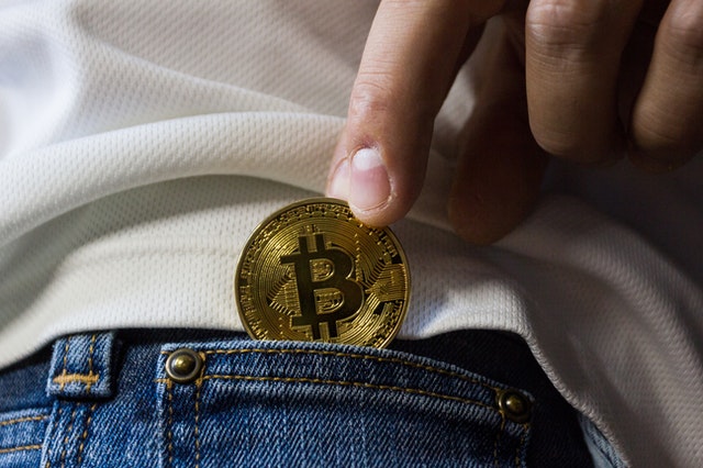 Bitcoin cryptocurrency being pulled out of a pocket.