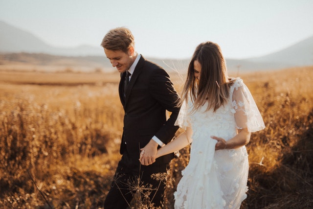 A wedding photographer captures a photo of a married couple in a field in Alabama.