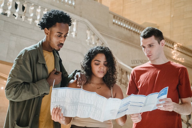 Three young people looking at a map planning their travel itinerary.