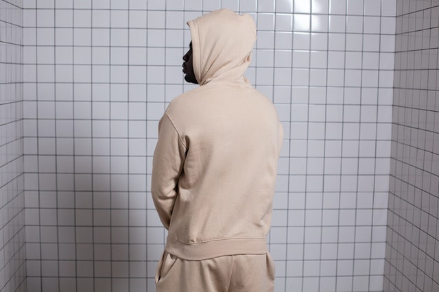 A man wearing a personalized hoodie facing the wall.
