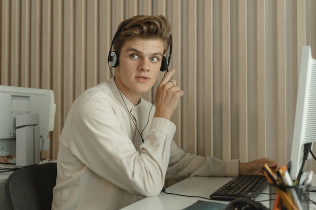 A member of an IT consulting firm in Los Angeles using a computer and headset to provide customer support.