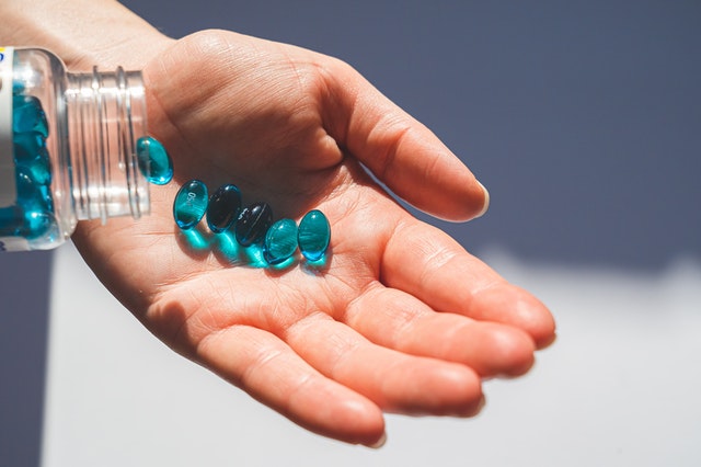 A person pouring blue weight loss product capsules into their hand.