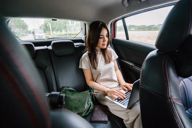 A woman writing a travel and lifestyle blog to follow in a car.